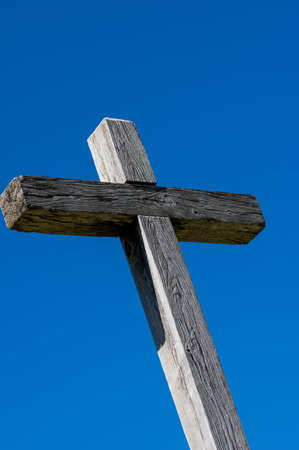 A wooden cross set against a blue sky with clouds.