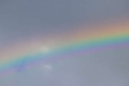 A small section of a colorfful rainbow in the dark stormy sky.の写真素材
