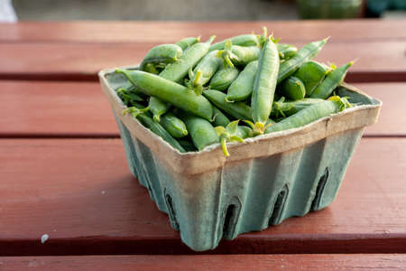 A small box of green peas on a table.
