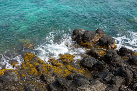 An aerial view of a rocky coast on a tropical island.