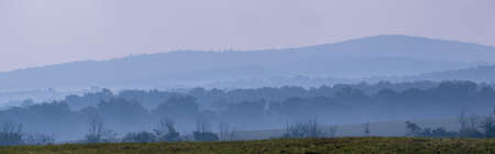 A panorama of the blue hour mist rising above the hills.