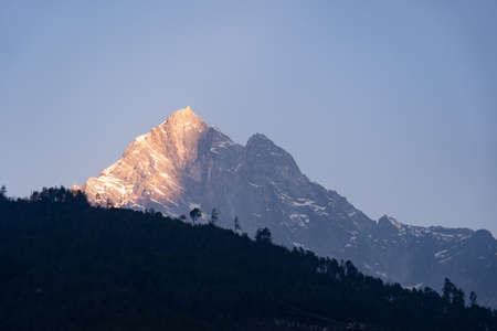 Early morning light touching the peak of a snow covered mountain.の写真素材