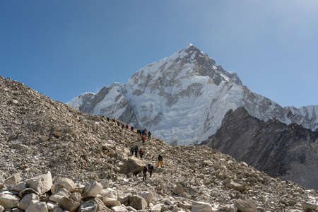 A long line of trekkers climbing over the rocks on the way to Everest Base Camp.