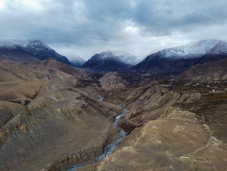 The beautiful clouds over the snow peaks of the Himalaya Mountains with the desert river valley in the foreground.の写真素材