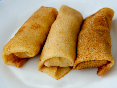 Thin pancakes on a white plate, close-up, horizontal