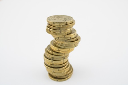 Unstable economy. Stack twenty euro cent coins on white background. Savings of coins.の写真素材