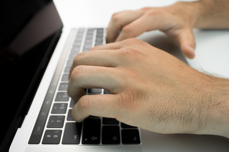 Hands using the keyboard and touchpad of a laptop computer on a white table. Modern workplace.の写真素材