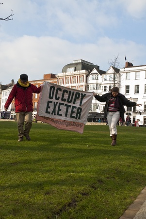 Occupy Exeter activist hold up an Occupy Exeter banner on Exeter Cathedral green during the Occupy...