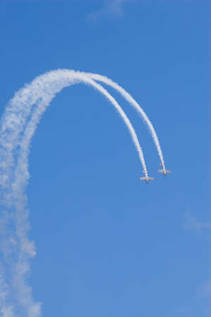 two planes loop the loop against a brilliant blue skyの写真素材