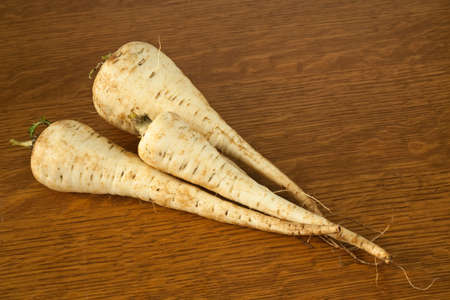 Three parsnips on a table ready to be prepared for a mealの写真素材
