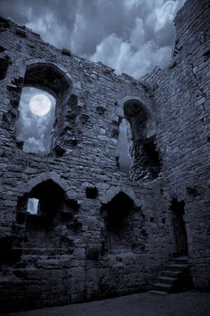 A very spooky Halloween castle in the moonlight, the moon is shining through a window.の写真素材