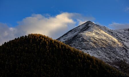 Mountain Landscape, Snow Covered Mountain Range - Daocheng Yading Nature Reserve. Ganzi, Garze, Kham Tibetan area of Sichuan Province China. Dramatic lighting during sunset, Clouds and Blue Skyの写真素材