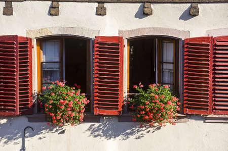 Barr (Bas-Rhin, Alsace, France) - Two windows of ancient white half-timbered house with red shutters and flowersの写真素材