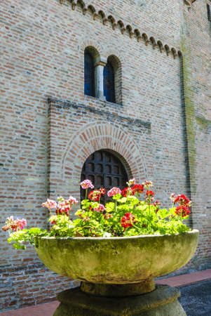 San Vito (Ferrara, Emilia Romagna, Italy) - Church in Romanesque style with flowers in foregroundの写真素材