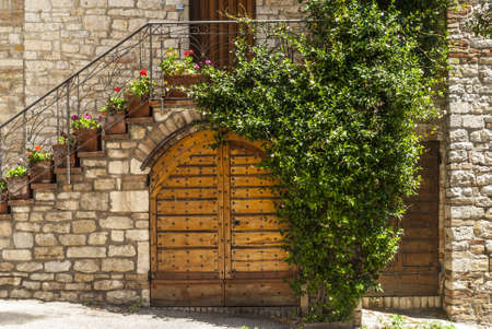 Corciano (Perugia, Umbria, Italy) - Stone circular well with flowers and clock towerのeditorial素材