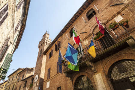 Buonconvento (Siena, Tuscany, Italy) - Historic buildings with clock tower and colorful flagsの写真素材