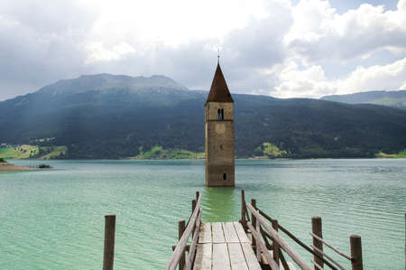 Resia (Bolzano, Trentino Alto-Adige, Italy): the famous tower in the lake and wooden pierの写真素材