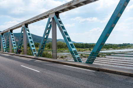Bridge over the Durance river near Manosque (Alpes-de-Haute-Provence, Provence-Alpes-Cote d'Azur, France) at spring with bicycleの写真素材