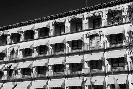 Toledo (Castilla-La Mancha, Spain): facade of historic building with balconies and yellow curtains in the Zocodover square. Black and whiteの写真素材