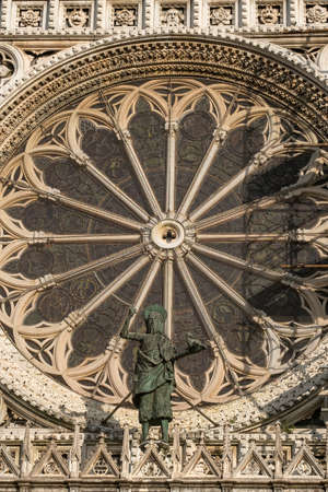 Monza (Brianza, Lombardy, Italy): historic cathedral exterior, detail of the facade (Duomo): rose window and a bronze statueの写真素材