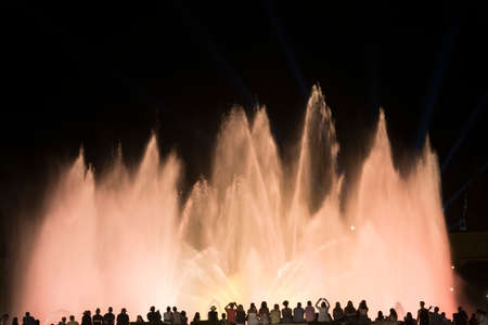 Barcelona (Catalunya, Spain): the Magic Fountain (Fuente Magica, Font Magica) of Montjuic, with plays of colorful lights at evening and people in silhouette watching at the showの写真素材