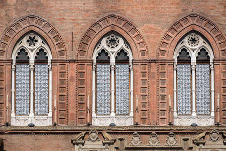 Bologna (Emilia Romagna, Italy): facade of historic building in a sunny morning. Three windows