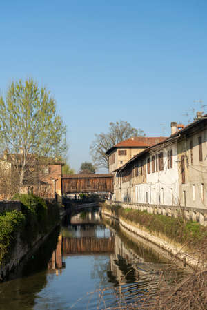Gorgonzola (Milan, Lombardy, Italy): old houses along the Martesana canal, with wooden bridge and bicycle laneの写真素材