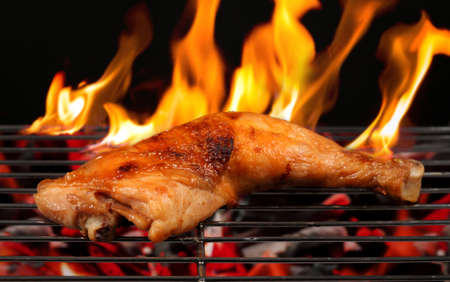 Grilled chicken Legs with flames on the grillの写真素材