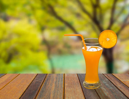Orange juice in glass on balcony with nature view behindの写真素材