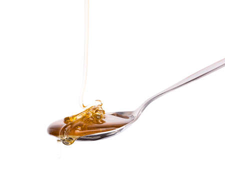 Honey dripping from a spoon isolated on white backgroundの写真素材