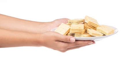 hand holding dish of Tasty biscuits isolated on white backgroundの写真素材
