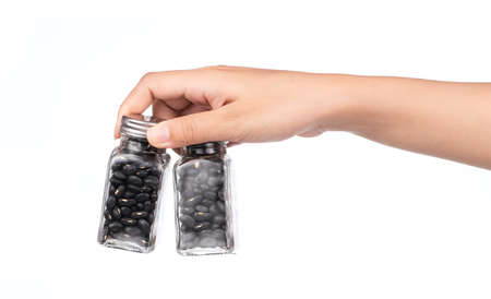 hand holding bottle of black beans isolated on white backgroundの写真素材