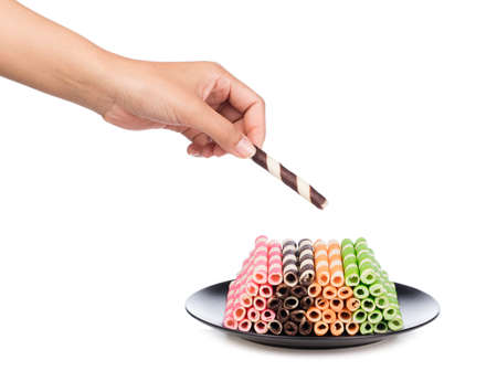 hand holding Striped wafer rolls filled on dish isolated on white backgroundの写真素材