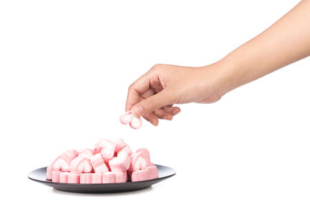 hand holding heart shape of marshmallow on dish isolated on white background.