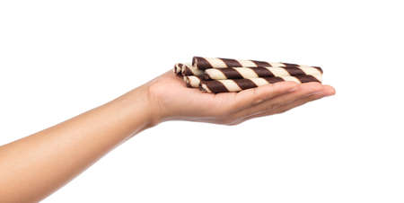hand holding Striped wafer rolls filled with chocolate isolated on white backgroundの写真素材