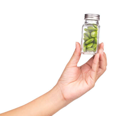 hand holding bottle of Parkia speciosa seeds isolated on white backgroundの写真素材