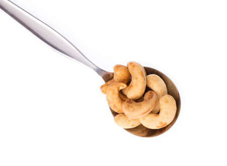 cashew nuts on spoon isolated on white backgroundの写真素材
