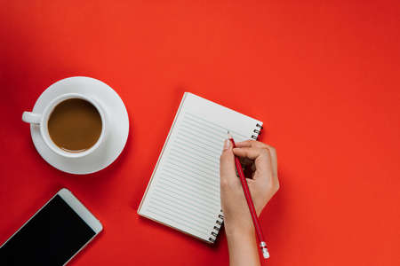 Background of red with smartphone, notebook and a cup of coffee の写真素材