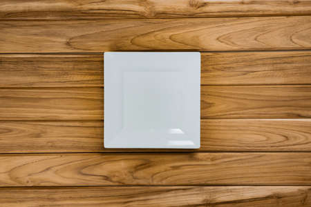 A white plate rests on wooden tableの写真素材
