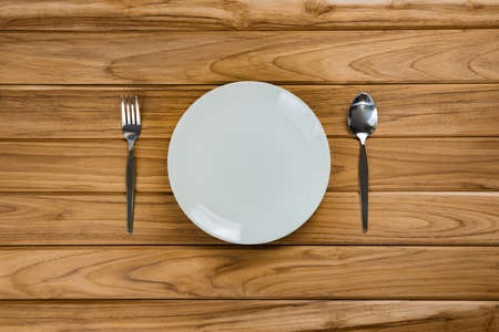 A plate with spoon and fork rests on wooden table