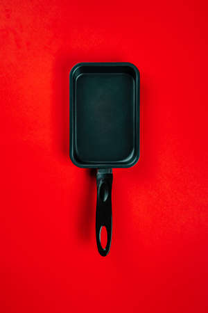 Black frying pans on red backgroundの写真素材