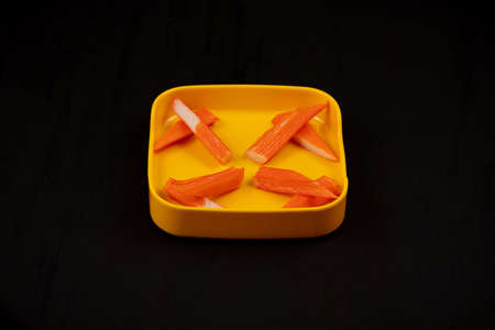 crab stick on yellow plate on wood backgroundの写真素材