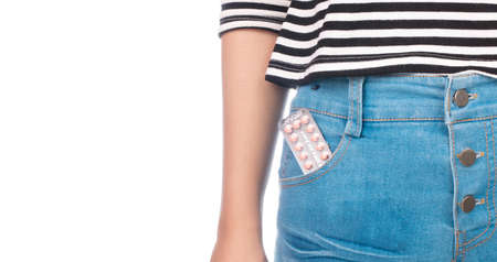 Birth control pill in the pocket of blue jeans isolated on white background