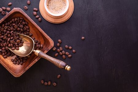 Coffee theme. Flat lay with place for text. Hot cup of coffee and plate with coffee beans on black wooden table.の写真素材