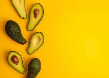 Ripe juicy halved  avocado on a yellow solid background with copy space. Vegan, vegetarian, raw food...
