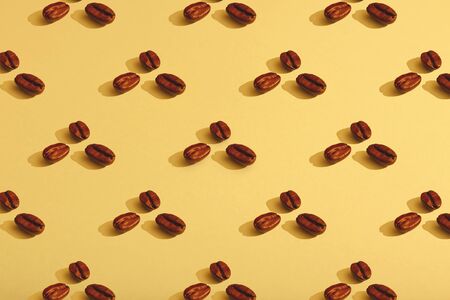 Coffee beans on yellow background. Flat lay, hard light.