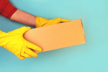 Box with ordered goods in the hands of a courier. Rubber gloves, contactless delivery. Quarantine, self-isolation.の写真素材