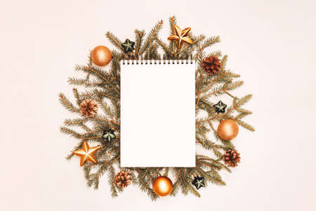 Notepad with holiday decorations in green and golden colors on white backdrop, copyspace. Christmas...