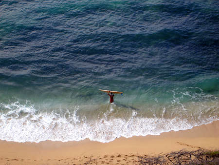 Aerial view of Surfer carrying surfboard into water, Diamond Head Beach, Hawaiiの写真素材