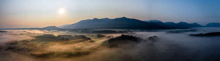 Aerial Panorama view of autumn sunset in mountains with fog and cloud valley landscape. Sun, Haze. Blomberg, Isartal, Bavaria. Duskの写真素材